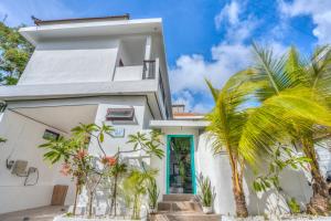 una casa bianca con una porta blu e palme di Villa iris Homestay a Uluwatu