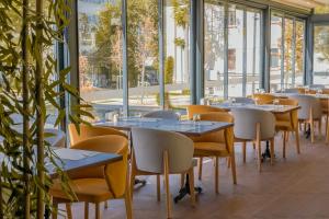 een rij tafels en stoelen in een kamer met ramen bij VE Hotels Adakale in Yenişehir