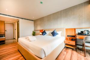 a bedroom with a large bed and a kitchen at Nestlay Suites by TC One in Kozhikode