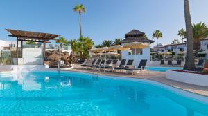 een zwembad op een resort met stoelen en parasols bij Boutique Hotel H10 White Suites - Adults Only in Playa Blanca