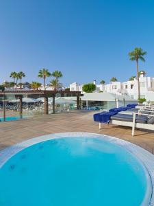 een groot zwembad in een resort met palmbomen bij Boutique Hotel H10 White Suites - Adults Only in Playa Blanca