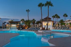 een zwembad met palmbomen en stoelen 's nachts bij Boutique Hotel H10 White Suites - Adults Only in Playa Blanca