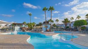 een zwembad op het resort met palmbomen bij Boutique Hotel H10 White Suites - Adults Only in Playa Blanca +57 foto's