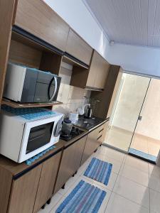 een keuken met een magnetron op een aanrecht bij Conforto a 100 m do mar in Tramandaí