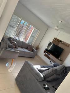 een woonkamer met een bank en een tv bij Conforto a 100 m do mar in Tramandaí