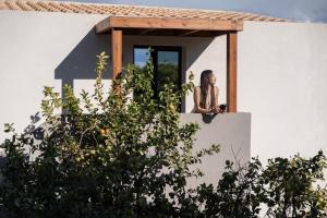 a woman sitting on a window ledge of a house at VAYA Suites by Omilos Hotels in Amoudara Herakliou +52 photos