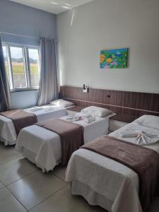 een kamer met drie bedden en een raam bij Miotto Executive Hotel in Navegantes
