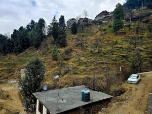 een auto geparkeerd op een heuvel naast een huis bij North Star Homestay Manali in Bashist
