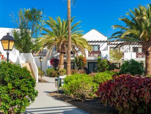 a resort with palm trees and a walkway at Boutique Hotel H10 White Suites - Adults Only in Playa Blanca