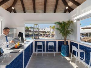 a man is sitting at a bar in a restaurant at Boutique Hotel H10 White Suites - Adults Only in Playa Blanca
