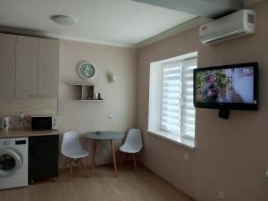a kitchen with a tv on the wall and a table at Современная студия-люкс, слобожанській in Samarovka
