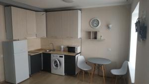 a kitchen with a refrigerator and a table and chairs at Современная студия-люкс, слобожанській in Samarovka