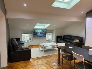 ein Wohnzimmer mit schwarzen Ledermöbeln und einem Tisch in der Unterkunft Le Savoyard in Saint Etienne