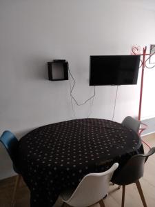 einen schwarzen Tisch mit Stühlen und einen TV an der Wand in der Unterkunft Le repos beaurepairien in Beaurepaire