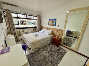 een slaapkamer met een bed en een grote spiegel bij Estudio Ao Lado do Parque - 15 mim do Aeroporto. in Brasilia