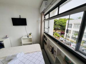een kamer met een bed en een groot raam bij Estudio Ao Lado do Parque - 15 mim do Aeroporto. in Brasilia
