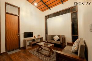 a living room with a couch and a tv at EKOSTAY - Forest Cube Villa in Attigundi