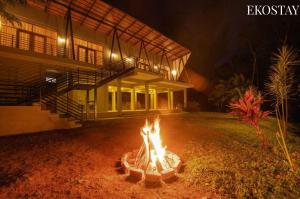 a fire pit in front of a house at night at EKOSTAY - Forest Cube Villa in Attigundi +4 photos