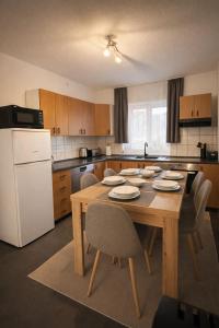 a kitchen with a wooden table with chairs and a white refrigerator at Apartman Mila in Golubić