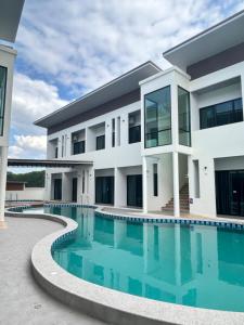 an exterior view of a building with a swimming pool at J&P Hotel Sriracha in Ban Laem Chabang
