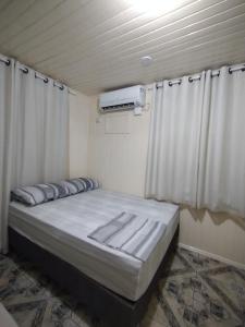 een bed in een kamer met een plafond met gordijnen bij Chalé com garagem fechada in Pântano Grande