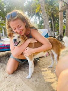 een vrouw die een hond knuffelt op het strand bij Secret Beach - Talalla in Talalla South
