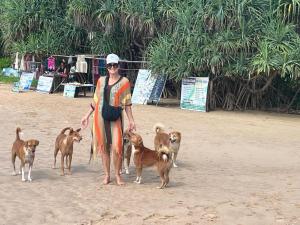 een vrouw staat met een paar honden op het strand bij Secret Beach - Talalla in Talalla South