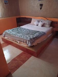 een bed met een houten frame in een kamer bij Gite take your time merzouga in Adrouine