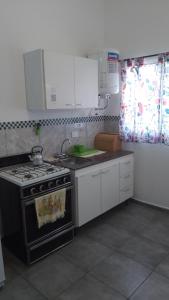 eine Küche mit einem Herd und weißen Schränken in der Unterkunft Departamento CR in Alta Gracia