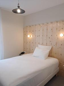 een slaapkamer met een groot wit bed en 2 verlichting bij Hôtel du Cheval Blanc Brunstatt in Brunstatt