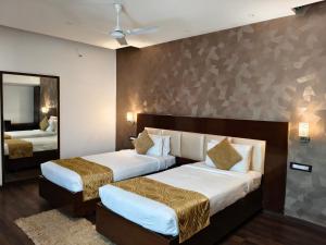 een hotelkamer met twee bedden en een spiegel bij Hemaadri Grand in Hyderabad +14 foto's