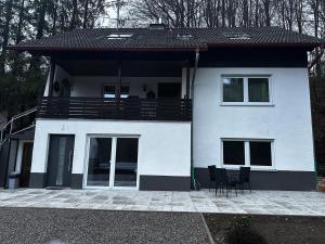 a white house with a balcony and two chairs at Waldhaus in Affing