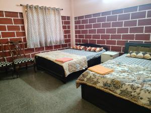 ein Zimmer mit zwei Betten und einer Ziegelwand in der Unterkunft Canara Highway Home Stay in Ankola
