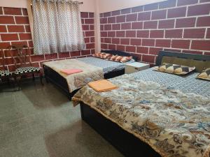 ein Zimmer mit zwei Betten und einer Ziegelwand in der Unterkunft Canara Highway Home Stay in Ankola