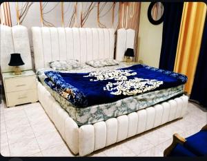 een groot wit bed met een blauwe deken erop bij Cozy Villa's in Rawalpindi