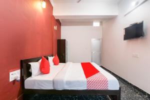 Schlafzimmer mit einem Bett mit roten Wänden und einem TV in der Unterkunft Hotel O Kavyanjali in Ayodhya
