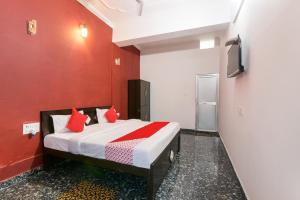 Schlafzimmer mit einem Bett mit roten Wänden und einem TV in der Unterkunft Hotel O Kavyanjali in Ayodhya