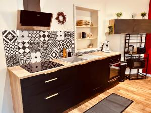 eine Küche mit einer Spüle und einer Fliesenwand in der Unterkunft Comme chez soi - Emplacement #1 et Grand Confort in Feurs + 8 Fotos