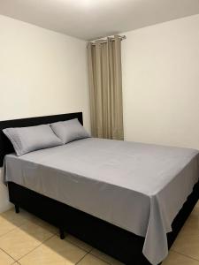 een slaapkamer met een groot bed en een witte deken bij Moradas do Embaú in Palhoça