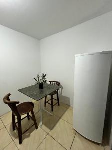 een tafel en stoel in een kamer met een koelkast bij Moradas do Embaú in Palhoça