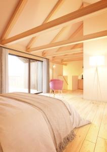 een slaapkamer met een groot bed en een roze stoel bij Bella Posta Hotel in Soprabolzano