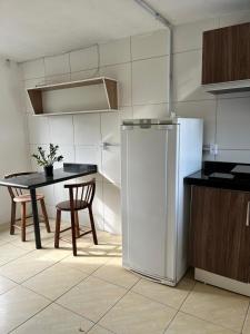 een keuken met een tafel en een witte koelkast bij Moradas do Embaú in Palhoça