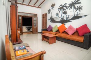een woonkamer met een bank met kleurrijke kussens bij Villa Prime Time Unawatuna in Unawatuna
