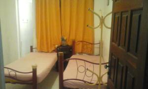 een slaapkamer met 2 bedden en een oranje gordijn bij Casa da Gorett in Salvador