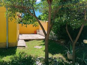 een achtertuin met een gele muur en een boom bij Chalet Paloma 3 in La Falda