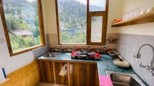 a small kitchen with a sink and two windows at The Himalayan Castle View Retreat in Nagar