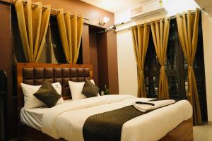 a bedroom with a large bed with yellow curtains at Elysia By THL-Near Westend Mall Aundh in Pune