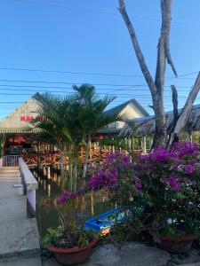 a resort with palm trees and a pond with flowers at Homestay Hải Nam Đất Mũi in Xóm Mũi