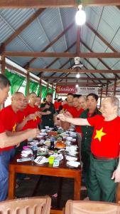 Xóm MũiHomestay Hải Nam Đất Mũi的一群人围坐在桌旁，吃着食物 更多25张照片