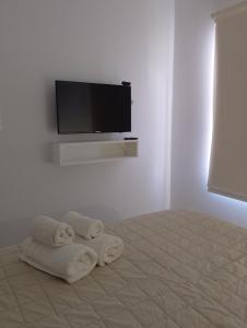 Cette chambre comprend un lit avec des serviettes et une télévision à écran plat. dans l'établissement El Estudio Céntrico con cochera, à Lobos